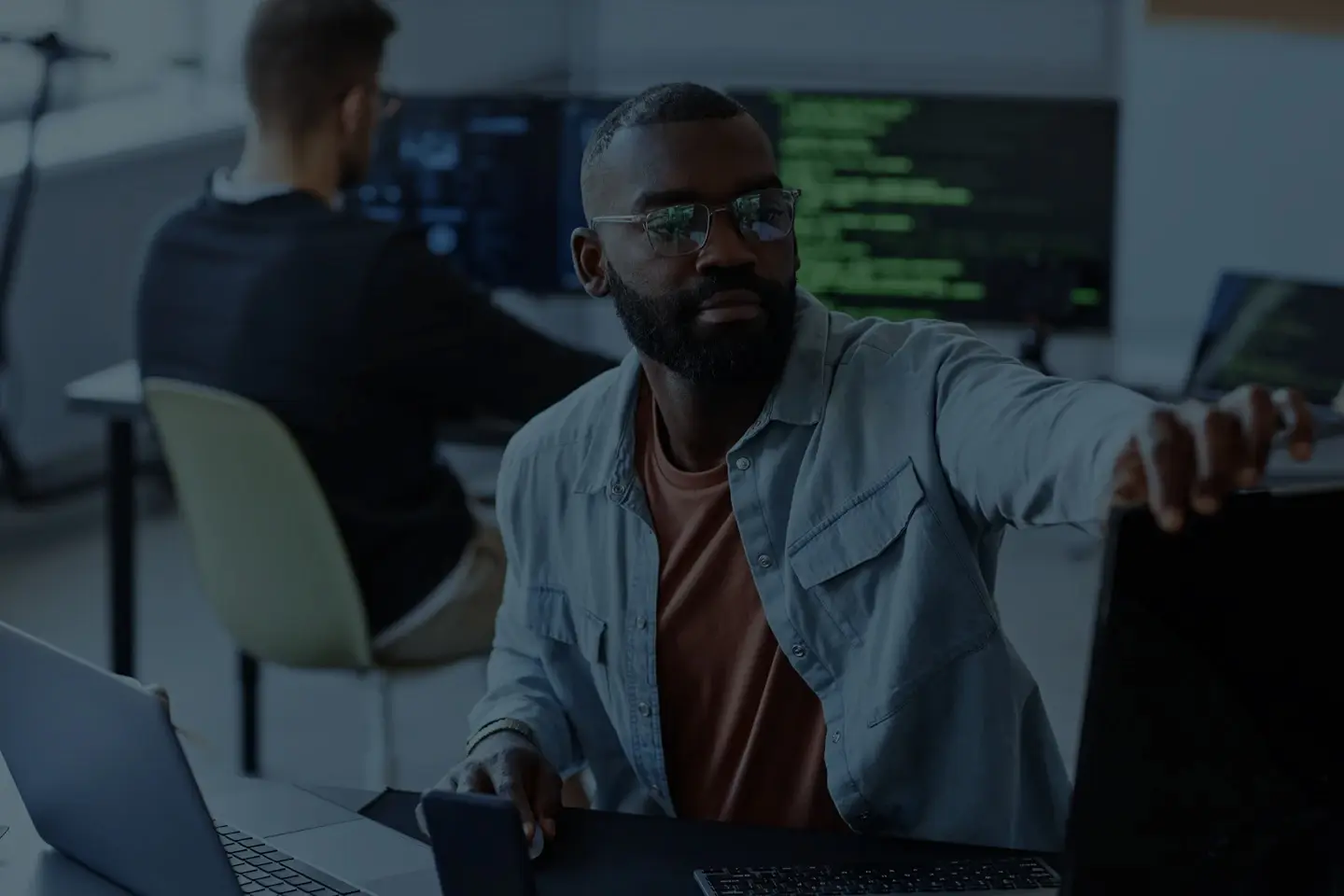 IT-Spezialist im modernen Büro vor Monitoren mit Code – authentisches Motiv für Außenwerbung Koblenz im Technologie-Umfeld